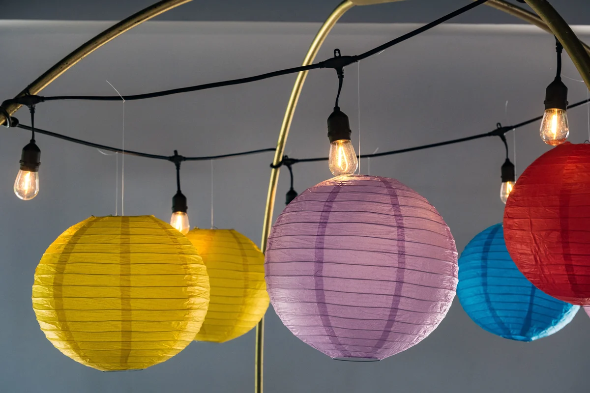 Faroles de papel de colores y focos colgantes como ambientación en Casa Martínez