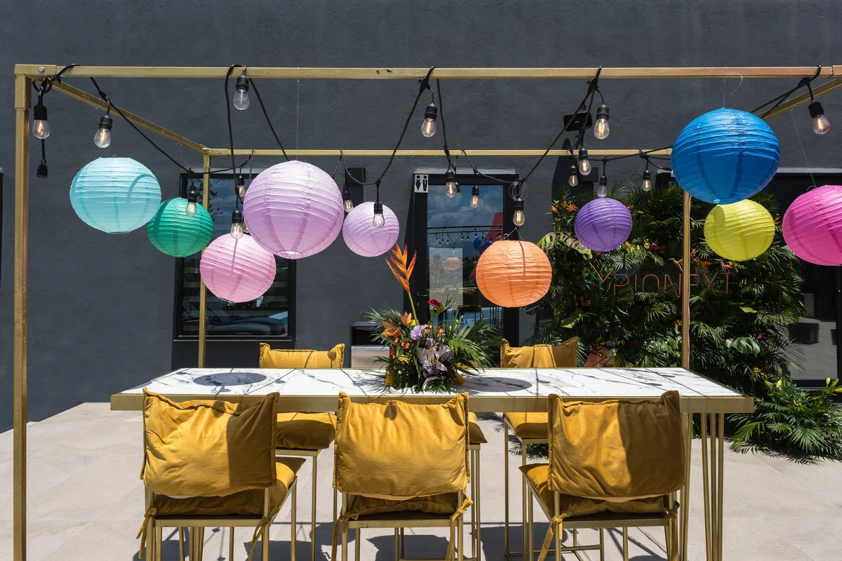 Mesa con sillas doradas bajo faroles de colores montada en la terraza de Casa Martínez