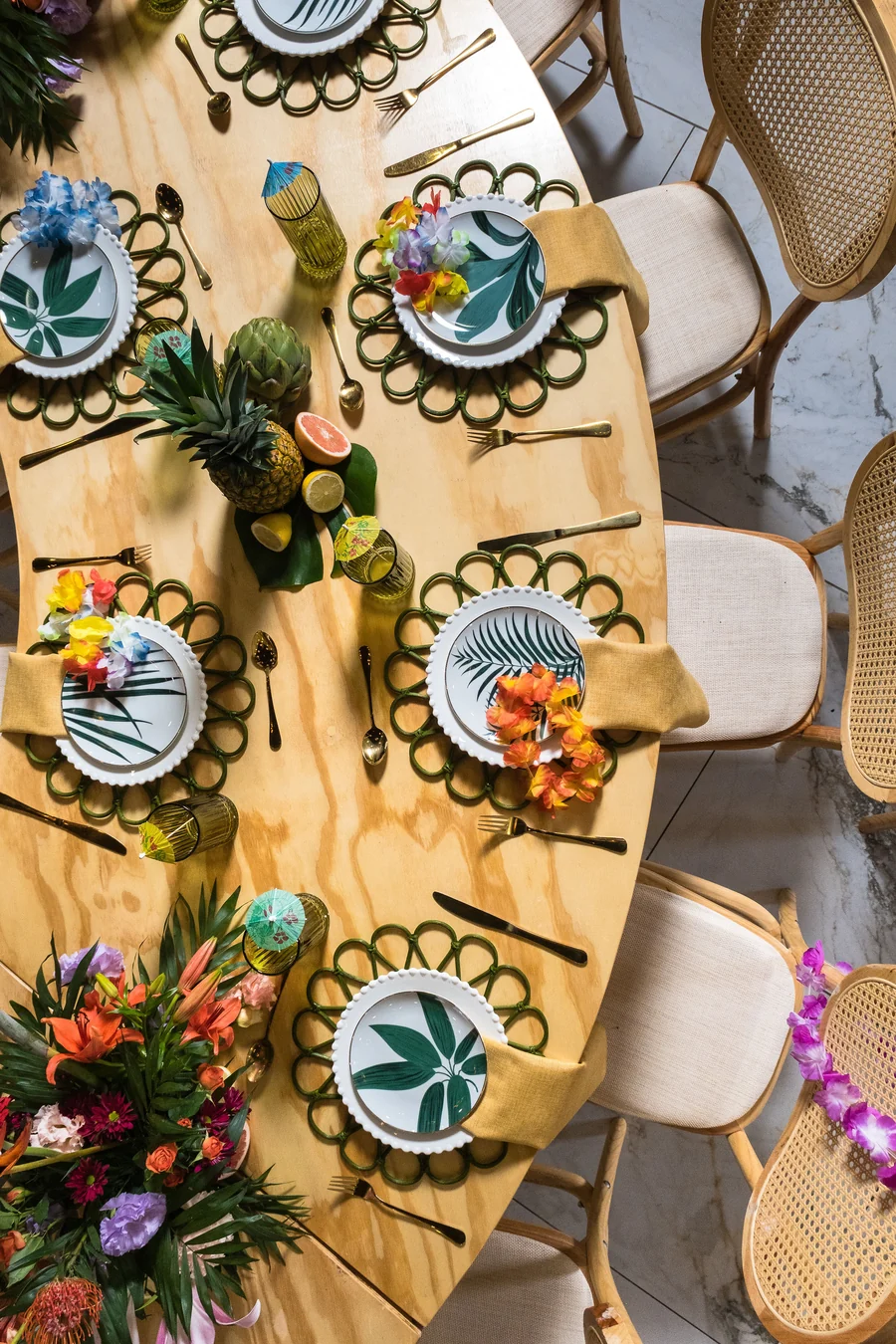 Vista superior de mesa con platos decorados y flores tropicales