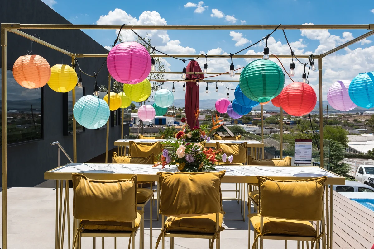 Mesa bajo estructura dorada con faroles de colores en la terraza junto a la alberca