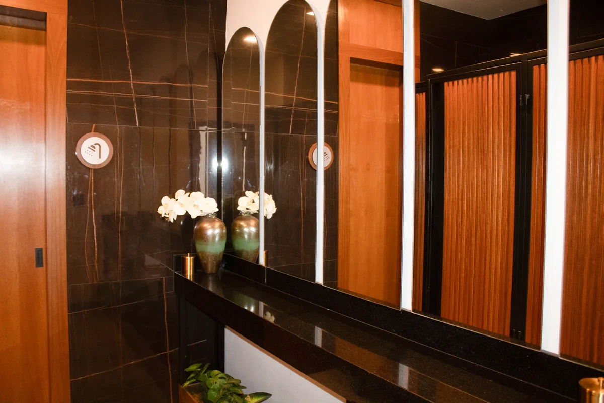 Baño de Casa Martínez con lavabo sobre cubierta oscura y espejos en arco