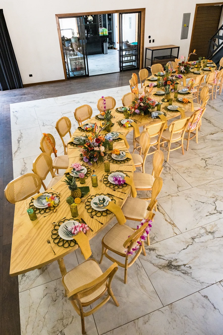 Mesa imperial con sillas de ratán y centros florales sobre el piso claro del salón de Casa Martínez